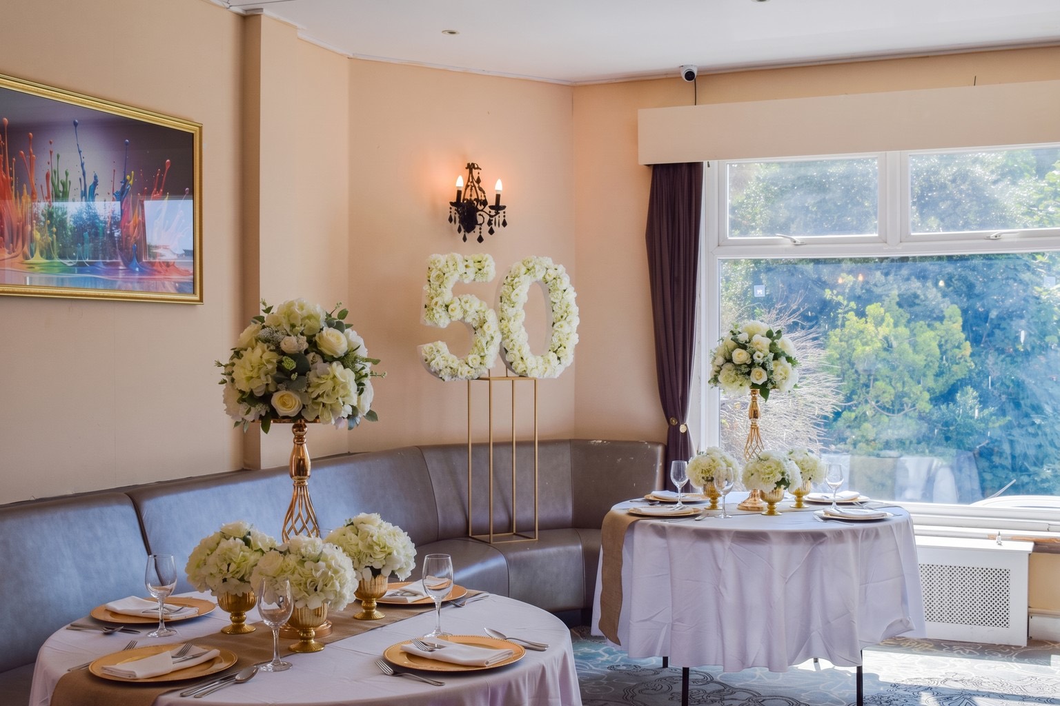 A milestone 50th birthday flower display beside a dressed table at Ashbury Lounge