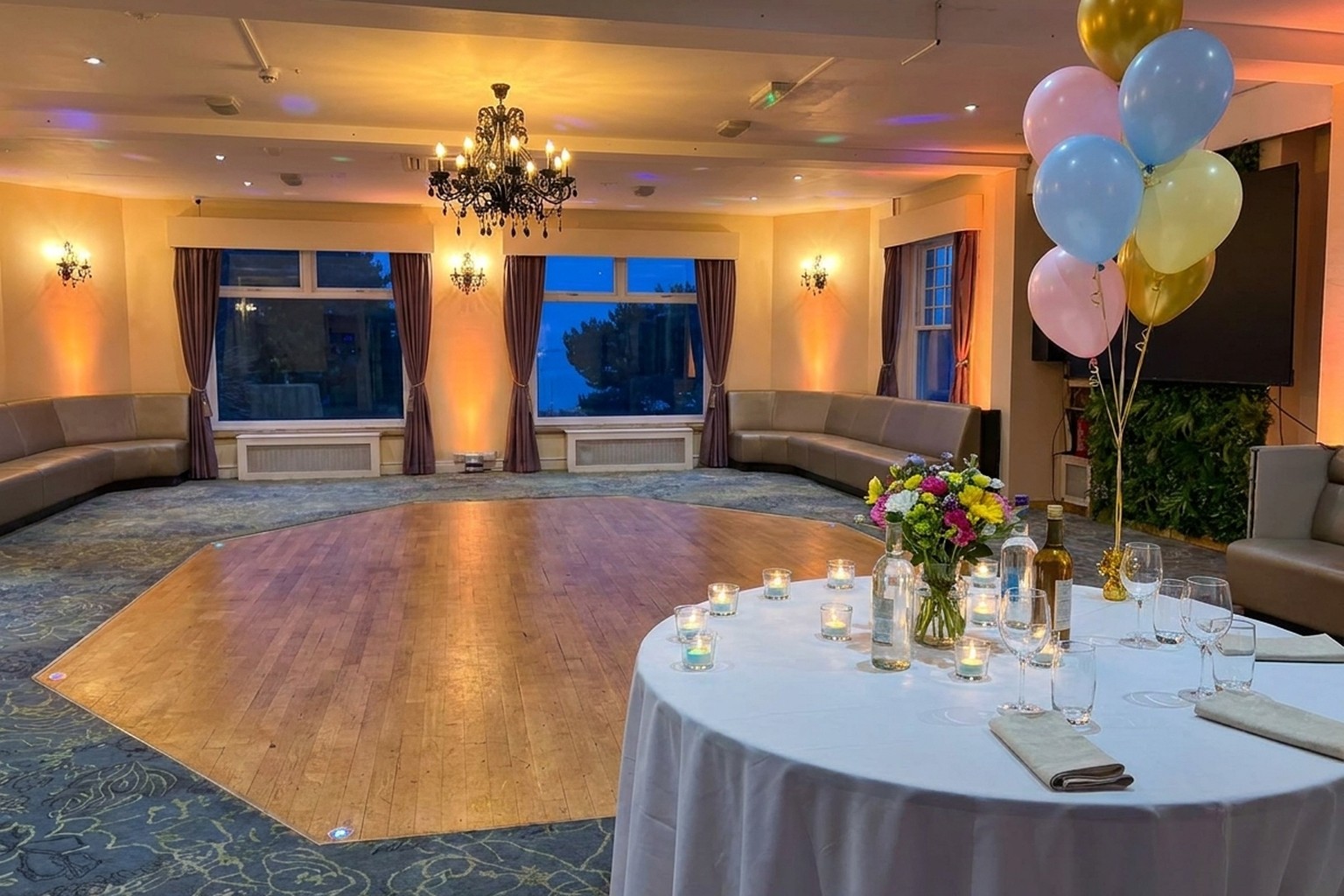The function room at Ashbury Lounge dressed for an evening, with a laid table and the lit dance floor beyond