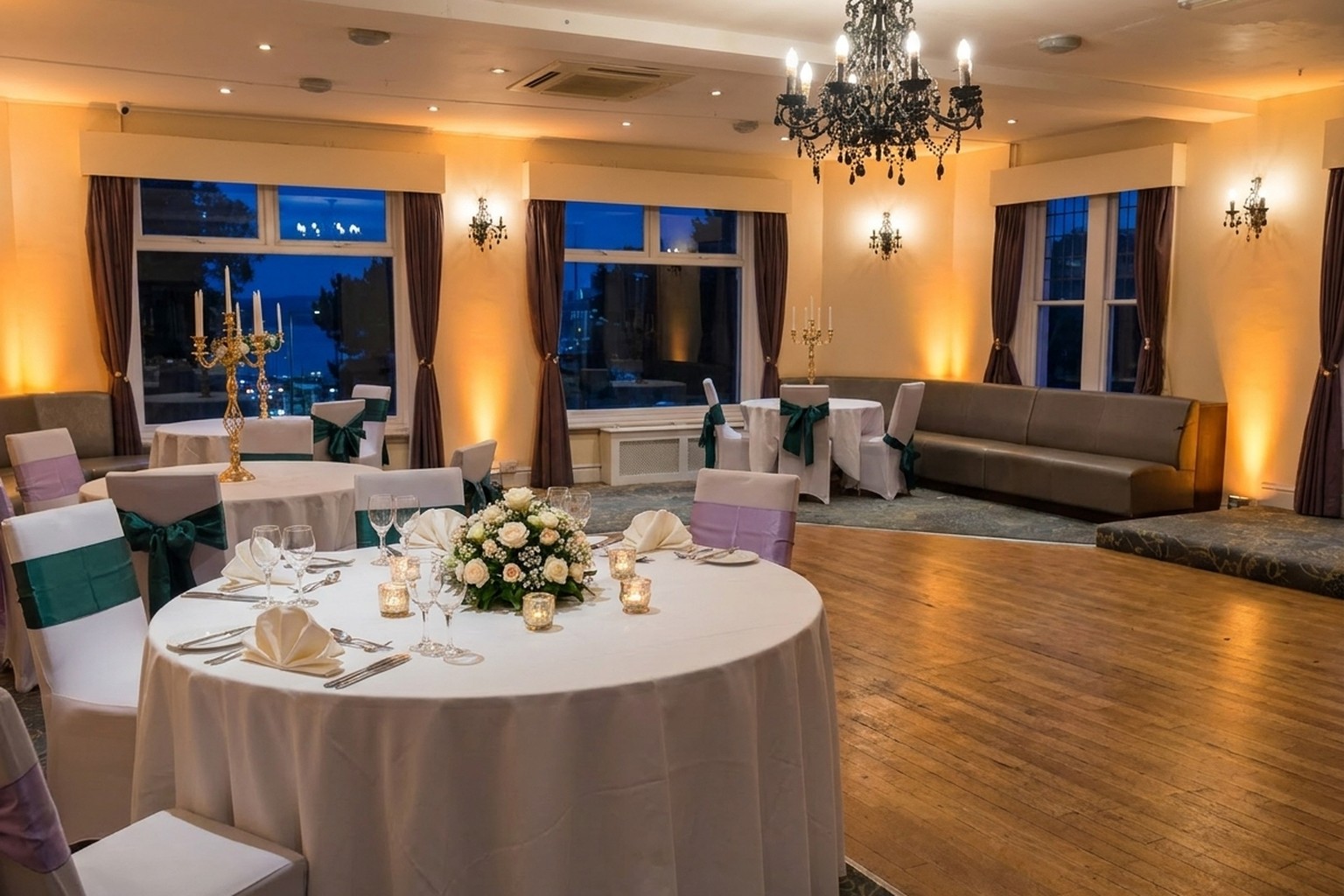 A round table in the Ashbury Lounge function room laid for a wedding meal, with white roses, glassware and tea lights