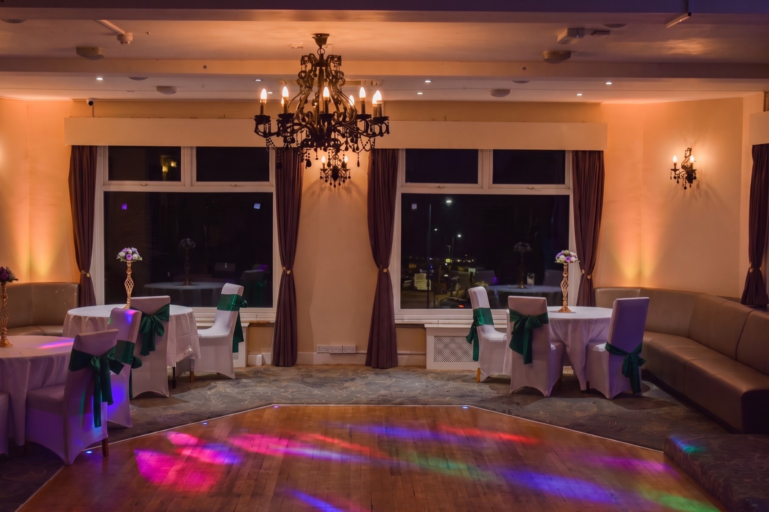 The dance floor at Ashbury Lounge lit in colour at night, with sashed chairs around the edge